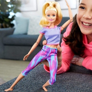 Fitnessdocka i Barbie-stil för flickor som spelas av en liten flicka i ett hus