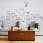 Väggdekoration med djurmotiv i svartvitt för flickor med en bakgrund i ett vardagsrum med soffa och bord