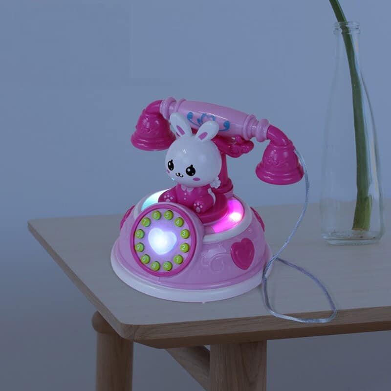 Telefonleksak för små flickor, rosa färger på ett bord i ett hus