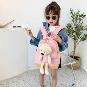 Ryggsäck med nallebjörn för flicka som bärs av en flicka i ett hus