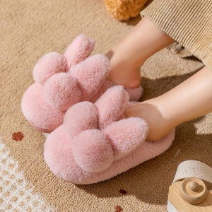 Mjuka rosa kanintofflor i plysch, bärs av ett barn
