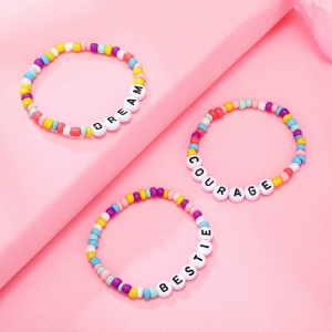 Pärlarmband med färgade bokstäver för en flicka mot en rosa bakgrund