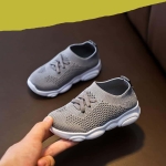 Ett par halkfria gråa gymnastikskor som hålls i handen av en vuxen