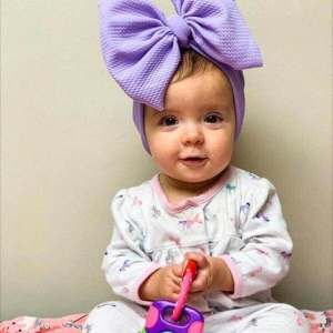 Trendig lila turbanhatt för små flickor som bärs av en liten flicka