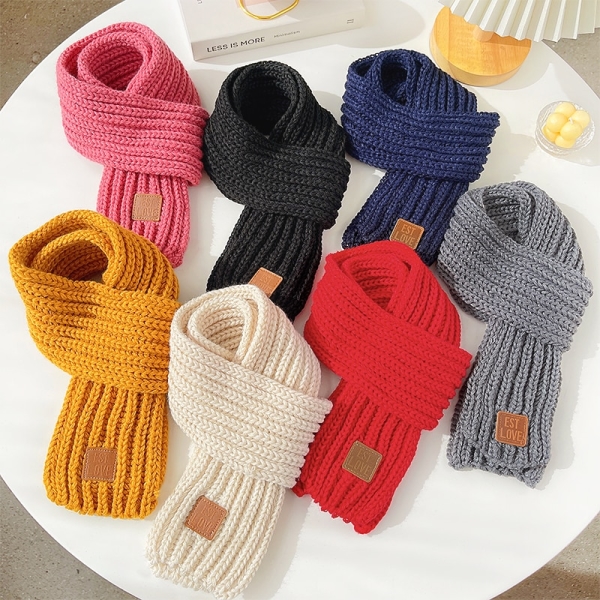 sju halsdukar knutna och upplagda på ett runt vitt bord, färgerna är rosa, svart, mörkblå, gul, vit, röd och grå på ett vitt bord