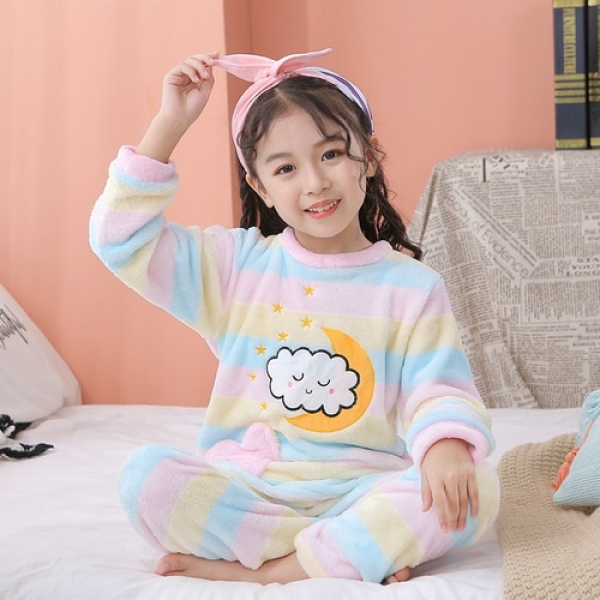 Pyjamas i fleece med motiv av månar och moln för flickor, bärs av en liten flicka i ett hus