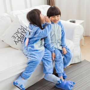 Pyjamasdräkt i blå tecknad fleece för flickor som bärs av en liten flicka och en liten pojke på en stol i ett hus
