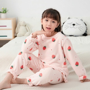 Söt rosa fleece-pyjamas för flickor som bärs av en liten flicka på en säng i ett hus