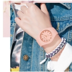 En ung flicka med bara överkroppen synlig, hon bär en jeansjacka och en vanlig rosa silikonklocka med armband