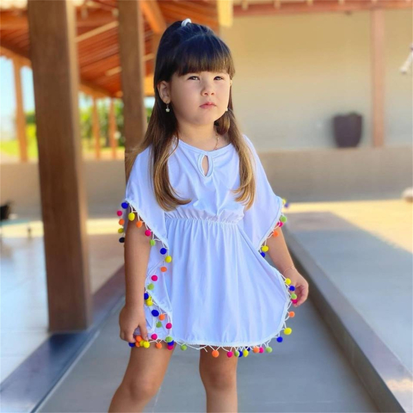 Vita strandkläder i sarongstil för flickor, bärs av en flicka som står utomhus