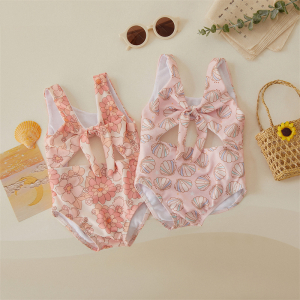 2 tryckta 1-dels baddräkter liggande platt med solglasögon, en väska och andra föremål runt dem