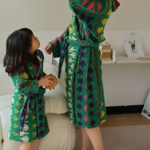 Ung brunettflicka med en vuxen i ett rum, båda bär gröna vegetabiliska badrockar
