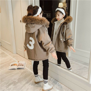 Ung flicka med vitt pannband och beige parkas framför en spegel