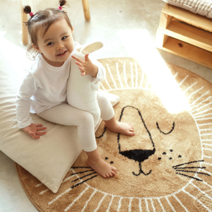 Barnrumsmatta i nordisk stil i form av ett lejon för en flicka med en liten flicka på mattan