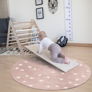 Baby leker på en rund matta i ett sovrum