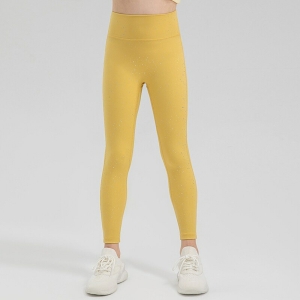 Ben av en ung flicka som står i glänsande gula sportleggings